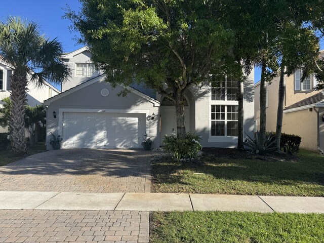 view of front of property featuring a garage, decorative driveway, and stucco siding