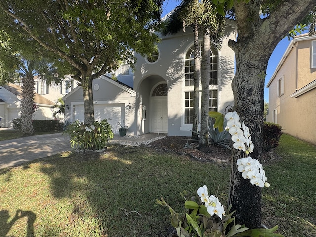 view of front of house featuring a garage, driveway, a front yard, and stucco siding