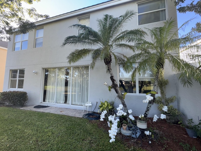 view of side of home with a lawn and stucco siding