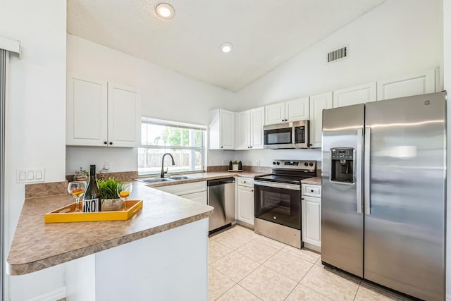 kitchen with visible vents, white cabinets, a peninsula, stainless steel appliances, and a sink