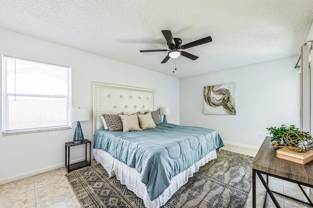 bedroom with ceiling fan, a textured ceiling, baseboards, and tile patterned floors