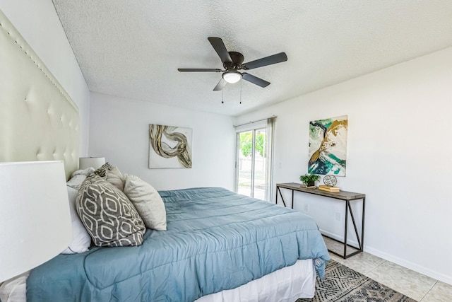 bedroom featuring a textured ceiling, ceiling fan, light tile patterned floors, baseboards, and access to exterior