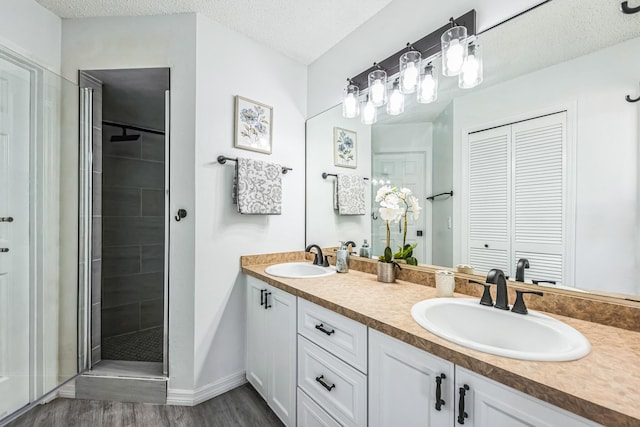 full bathroom featuring a textured ceiling, wood finished floors, a stall shower, and a sink