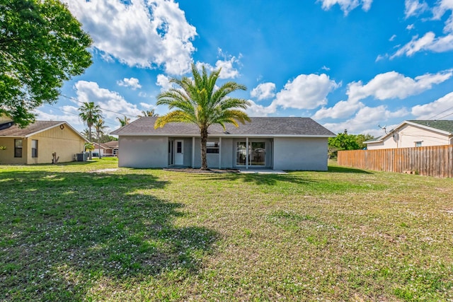 view of front facade with a front yard, fence, and stucco siding