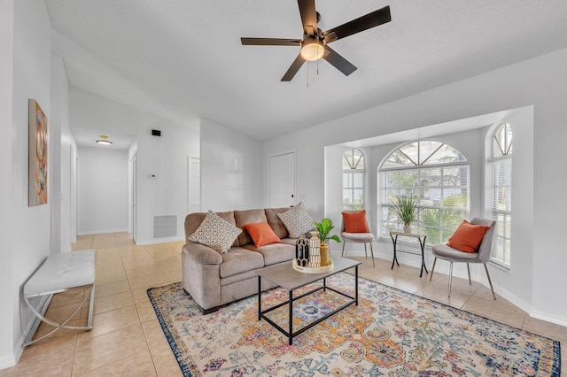 living room featuring light tile patterned floors, a ceiling fan, visible vents, vaulted ceiling, and baseboards