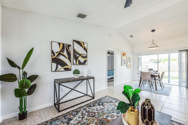 interior space featuring light tile patterned floors, lofted ceiling, visible vents, a ceiling fan, and a textured ceiling