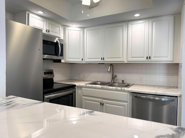 kitchen featuring stainless steel appliances, a sink, light countertops, and white cabinets