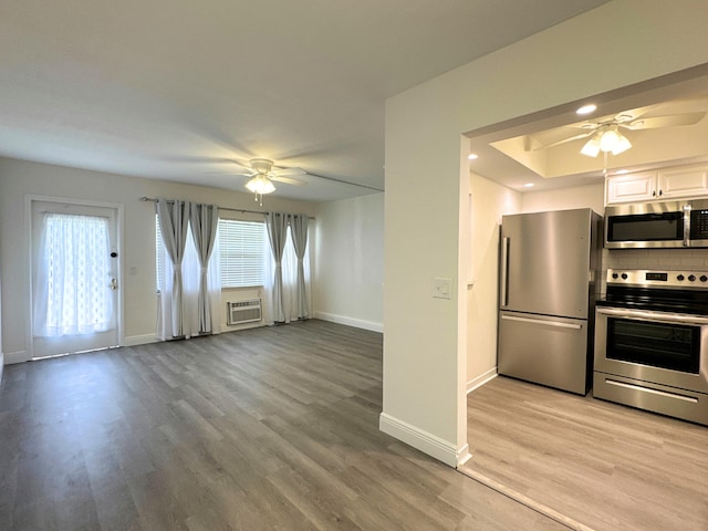 kitchen featuring stainless steel appliances, decorative backsplash, a ceiling fan, and light wood-style floors