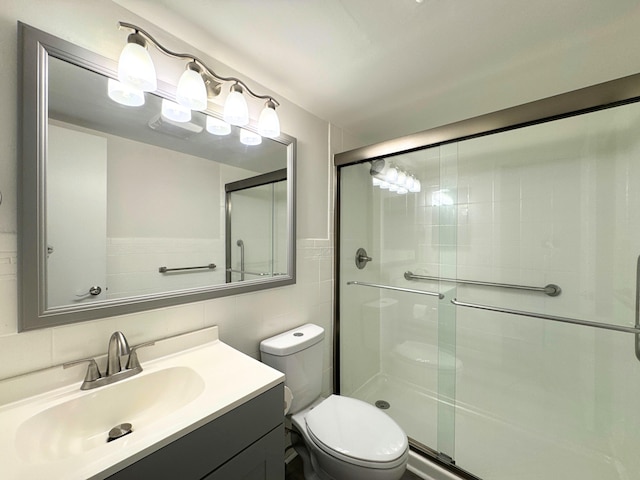 full bath featuring toilet, a stall shower, tile walls, and vanity