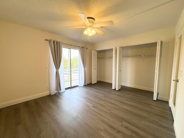 unfurnished bedroom with access to exterior, dark wood finished floors, a textured ceiling, and two closets