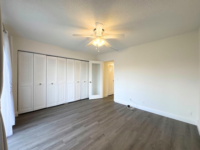 unfurnished bedroom with a closet, ceiling fan, a textured ceiling, wood finished floors, and baseboards