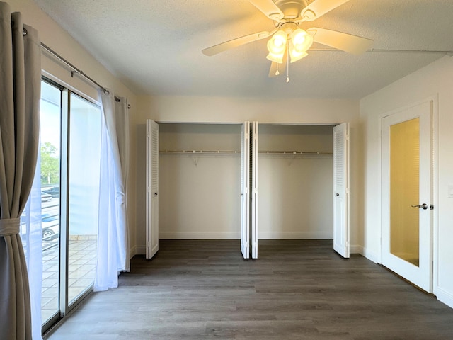 unfurnished bedroom featuring multiple closets, a textured ceiling, a ceiling fan, and wood finished floors