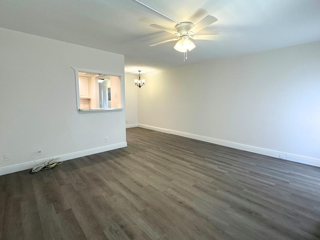 empty room featuring baseboards, dark wood-type flooring, and ceiling fan with notable chandelier