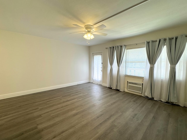 empty room featuring a wall unit AC, a ceiling fan, baseboards, and dark wood-type flooring