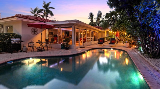 outdoor pool featuring a grill and a patio