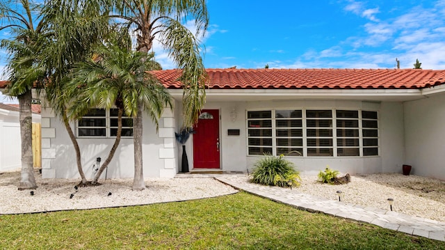 view of front of house featuring a front yard, a tile roof, and stucco siding