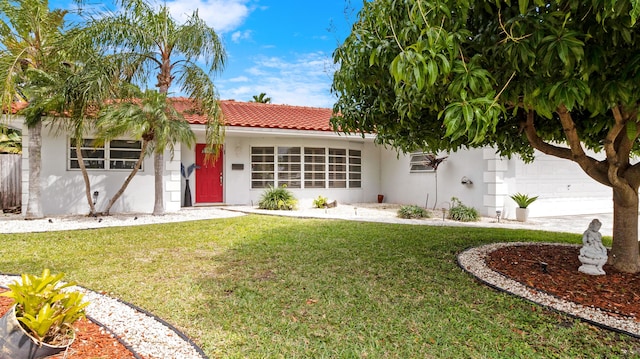 view of front facade featuring a tiled roof, a front lawn, an attached garage, and stucco siding