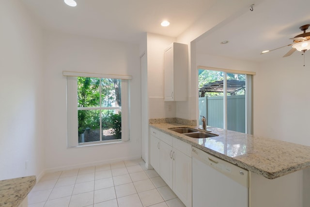 kitchen with light stone counters, white cabinets, a sink, dishwasher, and a peninsula