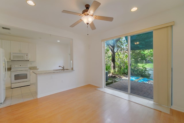 interior space with light wood finished floors, white appliances, visible vents, and white cabinetry