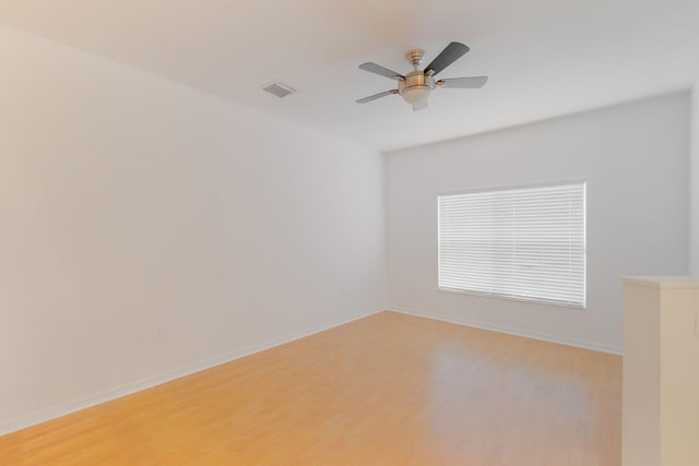 unfurnished room with a ceiling fan, light wood-type flooring, visible vents, and baseboards