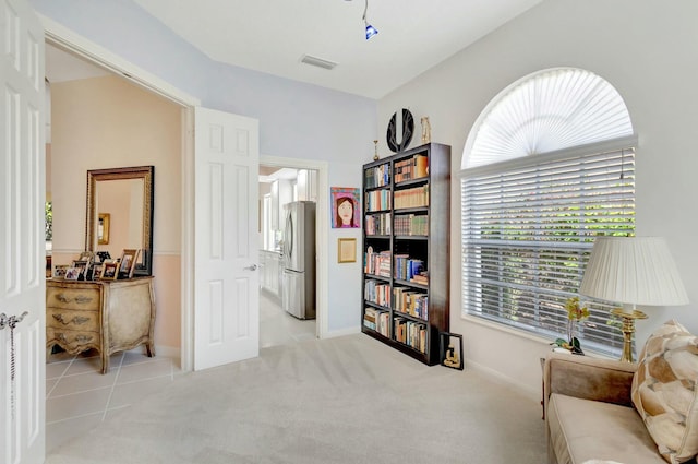 living area featuring light carpet, visible vents, and baseboards