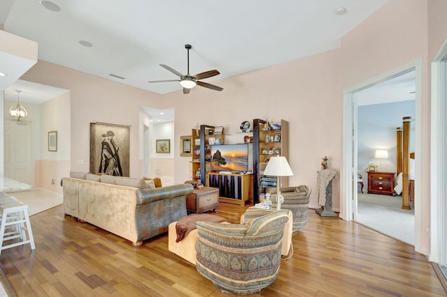 living area featuring visible vents, wood finished floors, and ceiling fan with notable chandelier