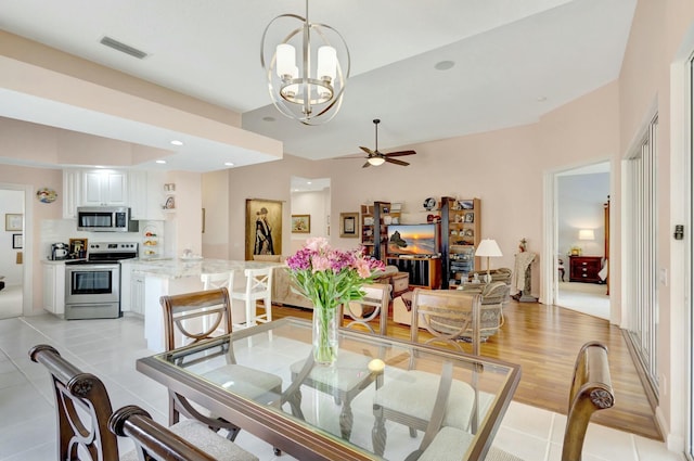 dining room featuring light tile patterned flooring, visible vents, ceiling fan with notable chandelier, and recessed lighting