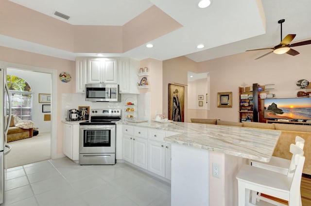 kitchen with visible vents, open floor plan, stainless steel appliances, a peninsula, and white cabinets