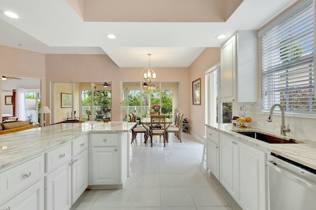 kitchen with light tile patterned floors, dishwashing machine, ceiling fan with notable chandelier, decorative backsplash, and a sink