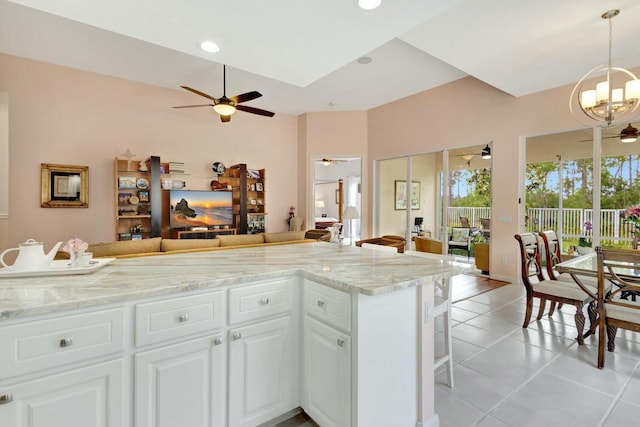 kitchen featuring a kitchen bar, decorative light fixtures, open floor plan, light tile patterned flooring, and white cabinets