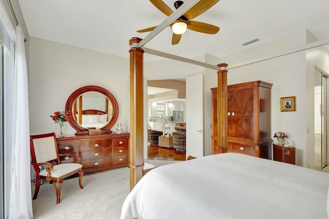 bedroom with visible vents, light colored carpet, and ceiling fan