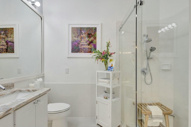 full bath with tile walls, a wainscoted wall, toilet, tiled shower, and vanity