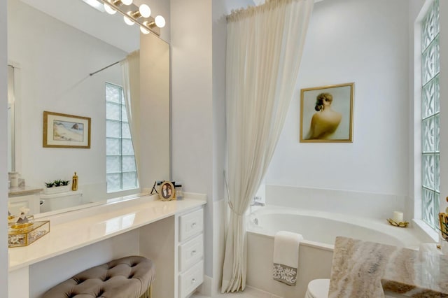 bathroom featuring toilet, a bath, and vanity