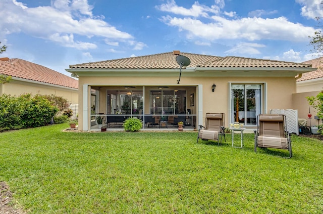 rear view of property with stucco siding, a lawn, a tile roof, and a sunroom