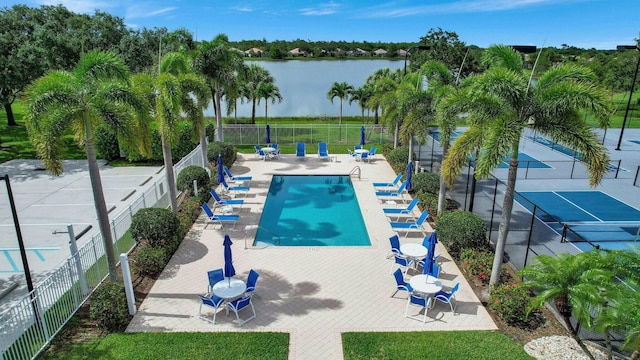 community pool with a water view, a patio, and fence