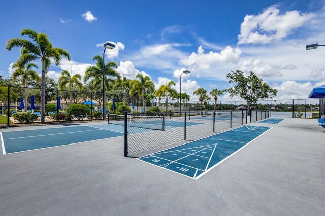 view of property's community with shuffleboard, a tennis court, and fence