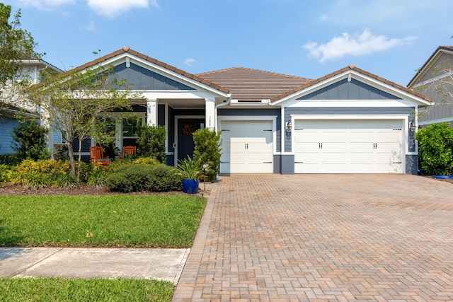 view of front facade with a garage, decorative driveway, a tiled roof, and board and batten siding