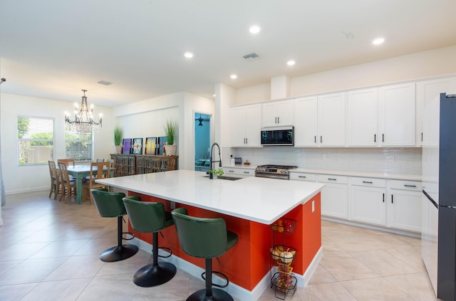 kitchen featuring a sink, decorative backsplash, a chandelier, and stainless steel appliances
