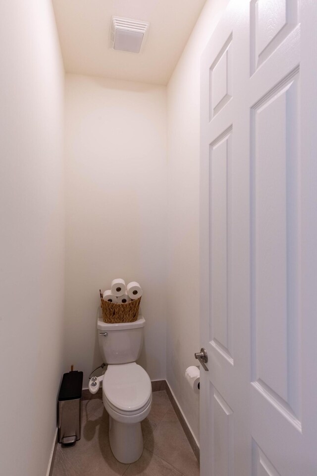 bathroom featuring toilet, baseboards, tile patterned flooring, and visible vents