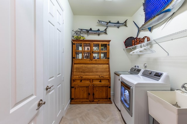 washroom with laundry area, washer and clothes dryer, a sink, and light tile patterned flooring