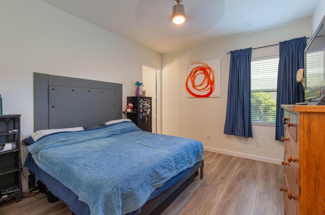 bedroom featuring ceiling fan, baseboards, and wood finished floors