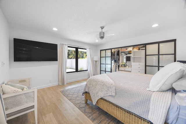 bedroom featuring a ceiling fan, wood finished floors, baseboards, recessed lighting, and a textured ceiling