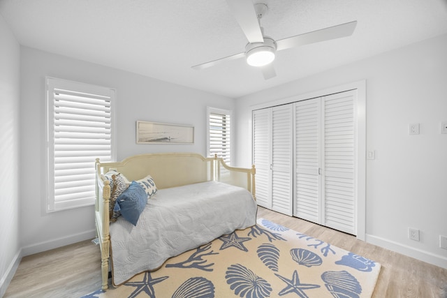 bedroom with a closet, a ceiling fan, baseboards, and wood finished floors