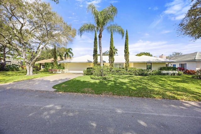 ranch-style home with a front lawn, a garage, driveway, and stucco siding