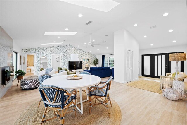 living room with wallpapered walls, vaulted ceiling with skylight, a healthy amount of sunlight, and a tile fireplace