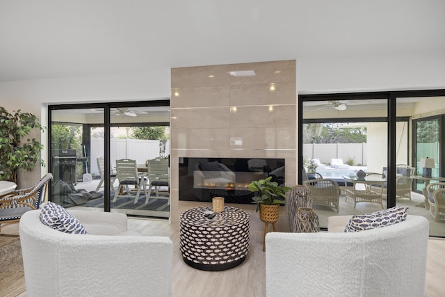 living room featuring a ceiling fan, wood finished floors, plenty of natural light, and a fireplace