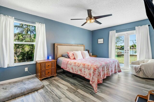 bedroom with multiple windows, wood finished floors, and access to outside