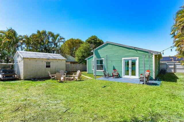 back of house featuring french doors, a fire pit, a lawn, and fence