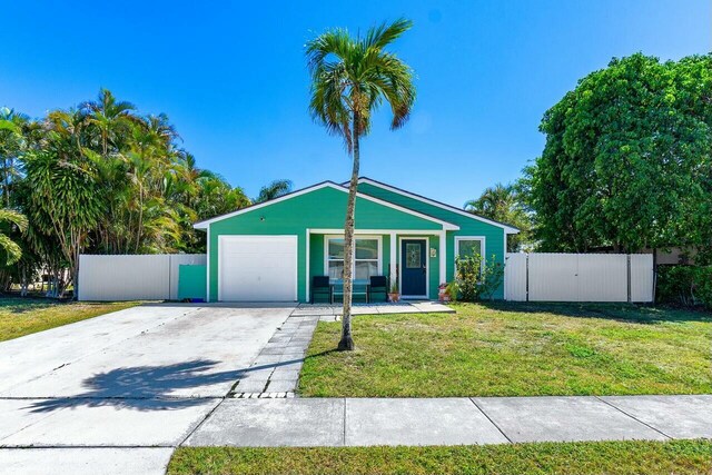 view of front of property featuring an attached garage, concrete driveway, a front yard, and fence