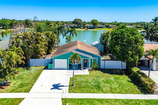 view of front of house featuring a water view, a front lawn, driveway, and fence